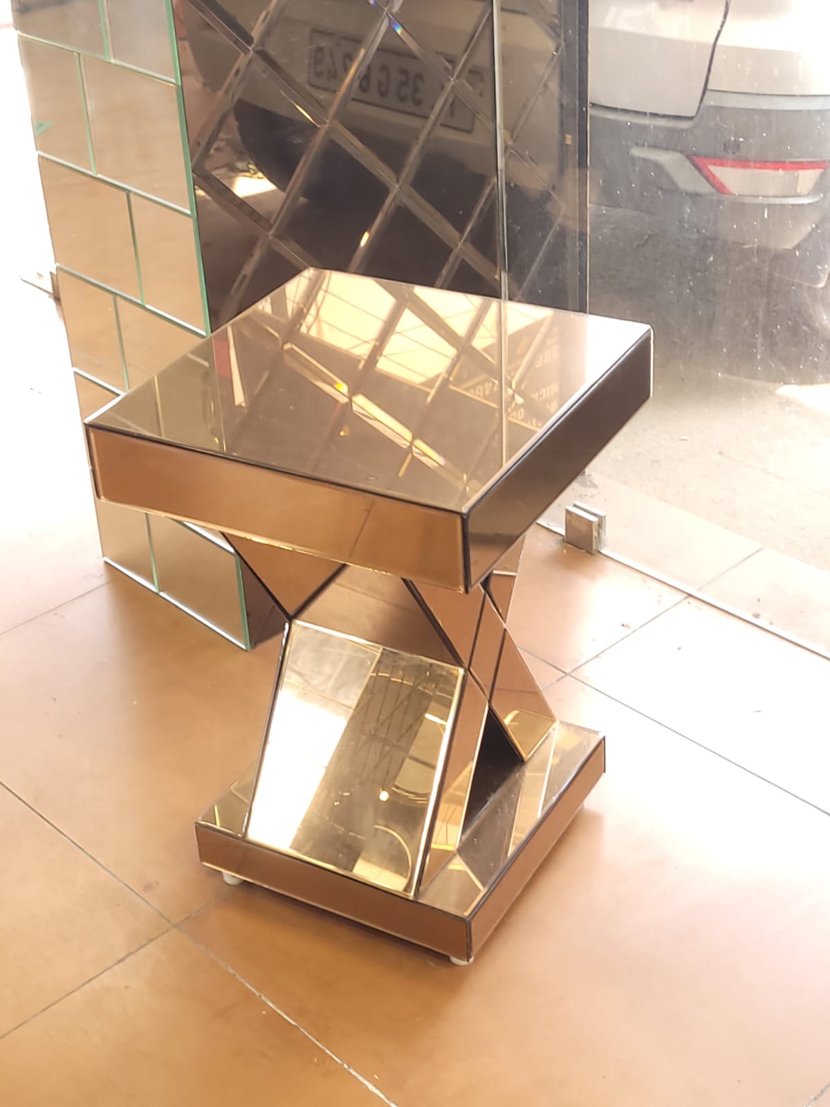 Cross-base mirrored table — A square mirrored tabletop on a crossed geometric base.
