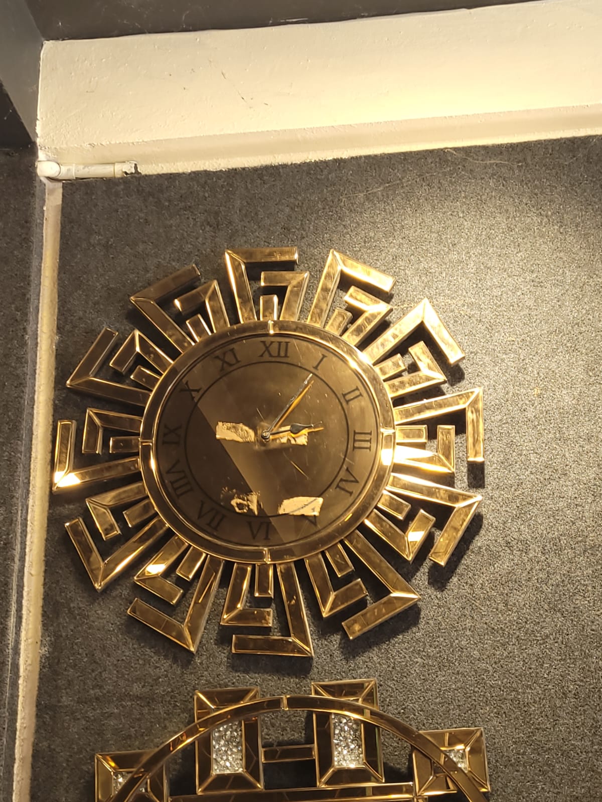 Gold geometric clock — Angular gold-toned mirror details frame a round clock face.