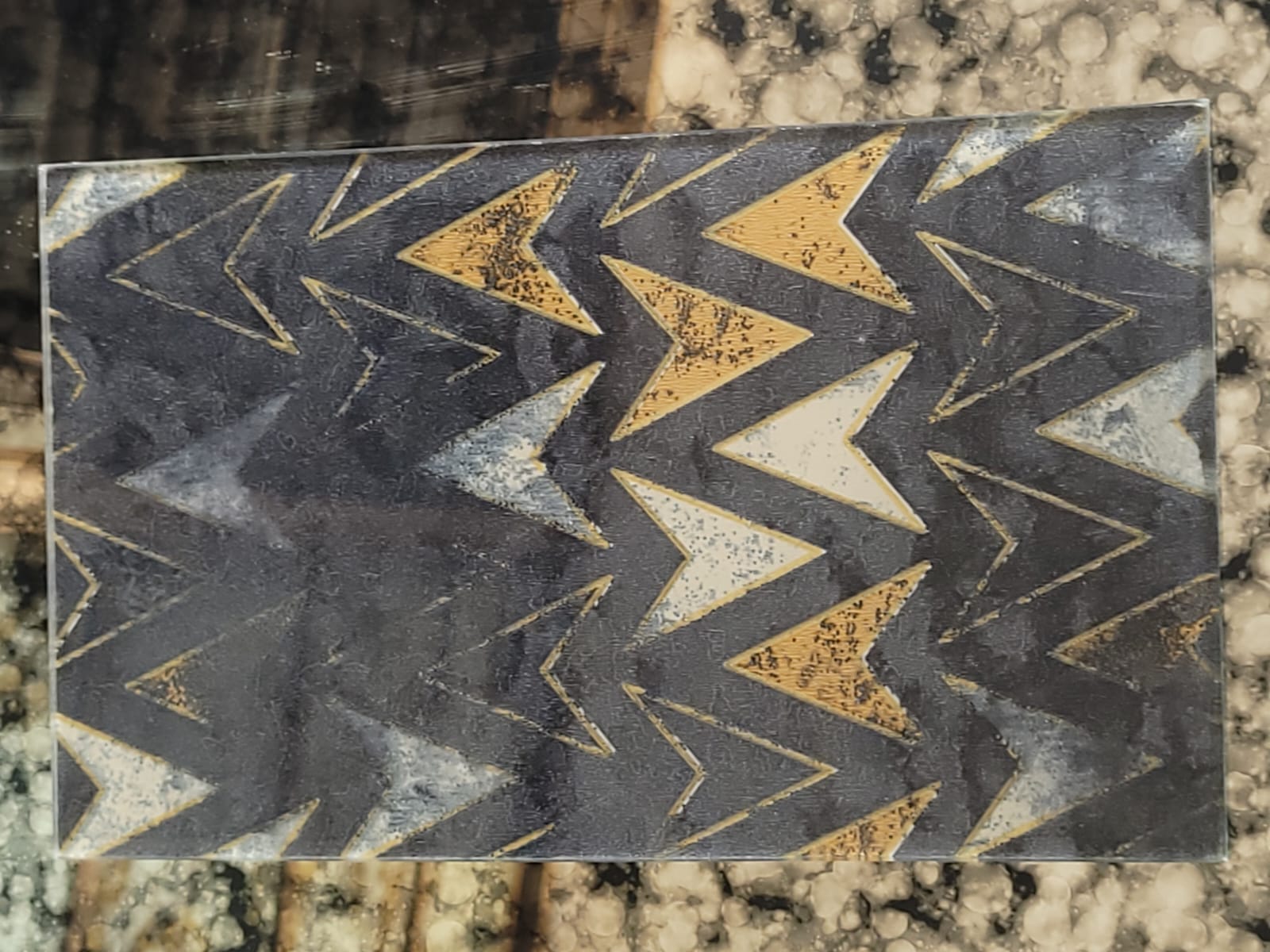 Chevron-pattern glass — Alternating gold, grey and white chevrons.