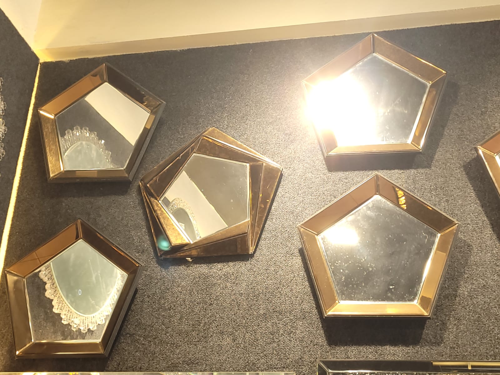 Pentagonal wall mirrors — A wall arrangement of gold-toned pentagonal mirrors.